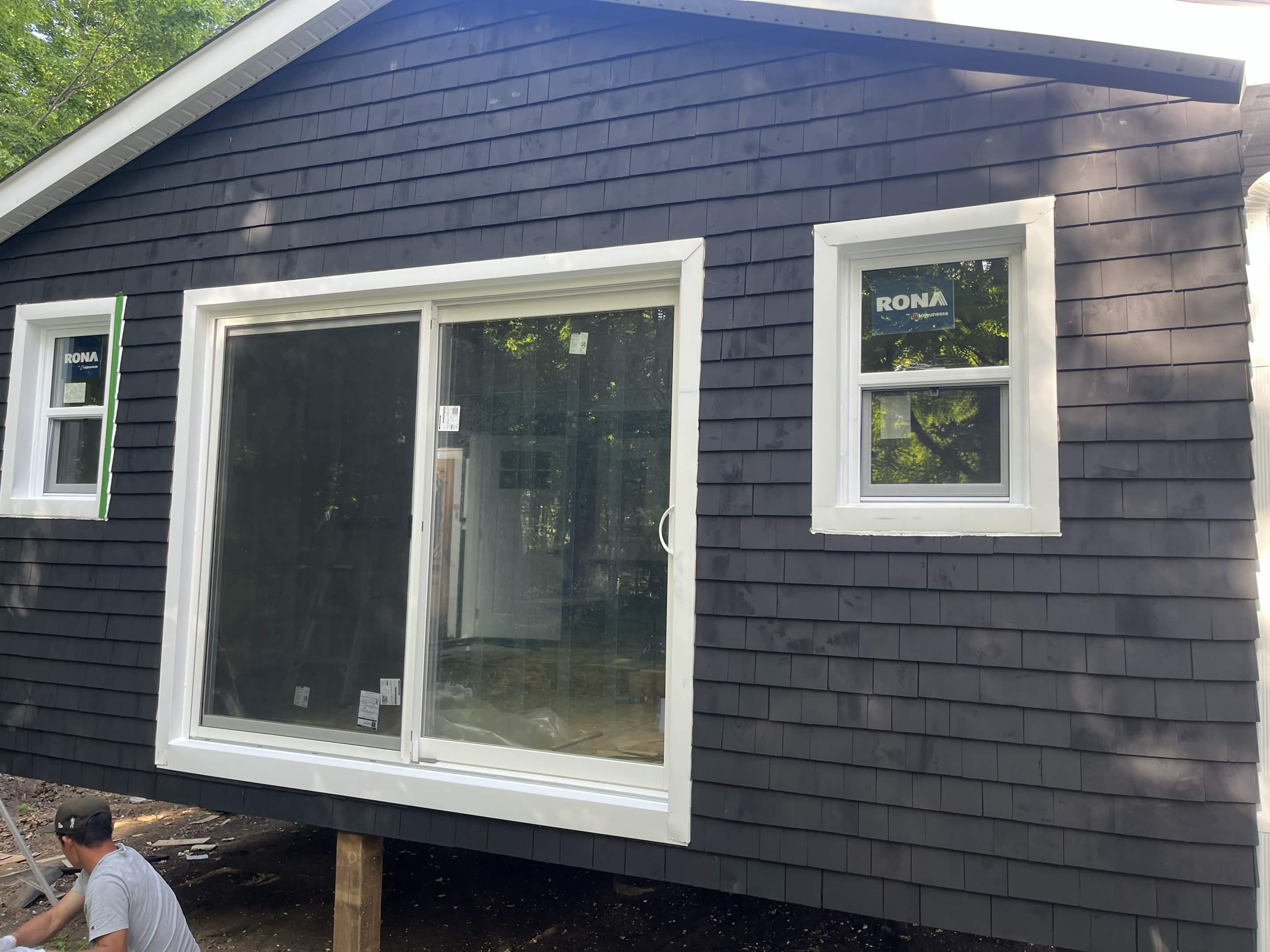 Completed exterior with dark shingle siding and white window trim